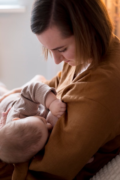 彼女のかわいい赤ちゃんを母乳で育てる若い女性