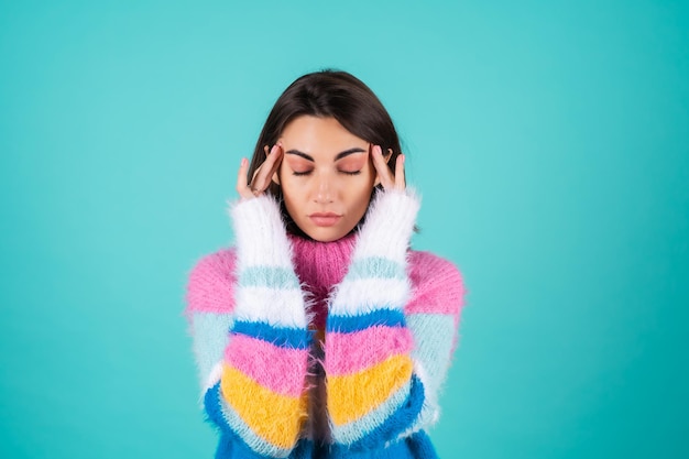 Young woman in a bright multi-colored sweater on blue