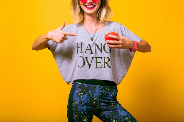 Young woman in bright sportive outfit playing with apple