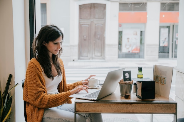 Young woman browsing laptop in cafe