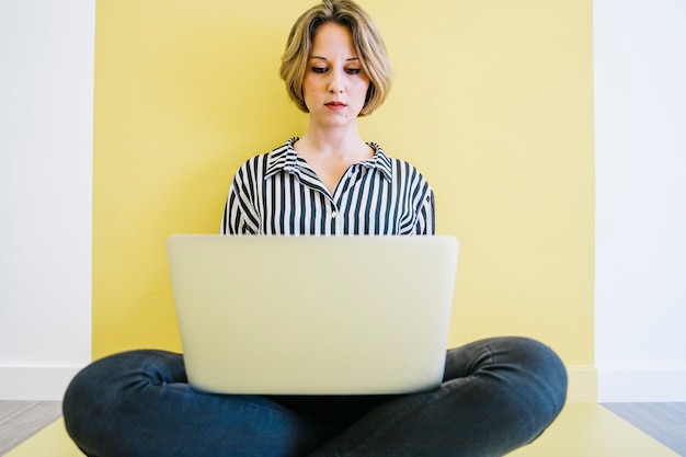 Free photo young woman browsing laptop on floor