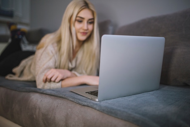 Foto gratuita computer portatile di lettura rapida della giovane donna sul sofà