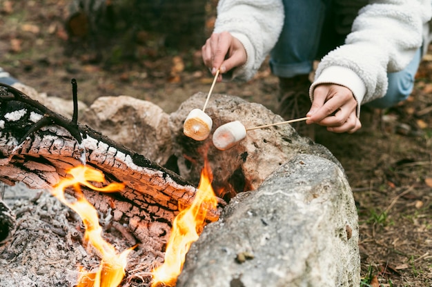 冬のキャンプファイヤーでマシュマロを燃やす若い女性