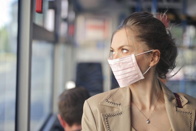 Free photo young woman in a bus with mask