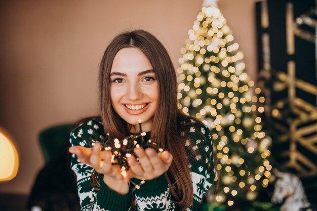 クリスマスの白熱灯とクリスマスツリーで若い女性