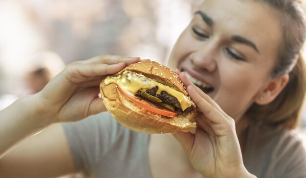 Young woman in cafe eating tasty sandwich