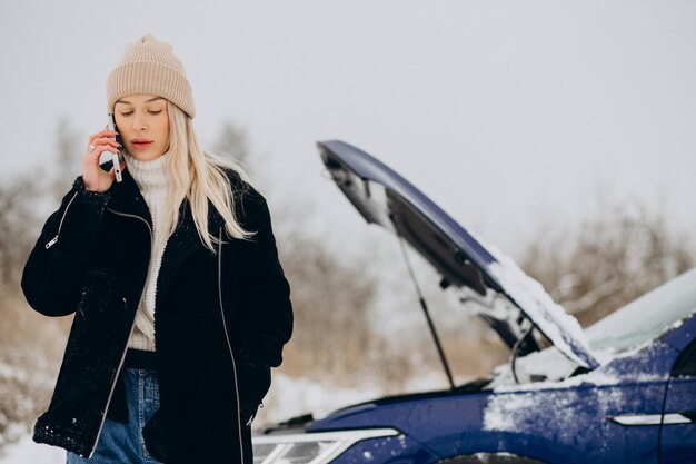 Young woman calling on the phone after her car brokedown in winter season