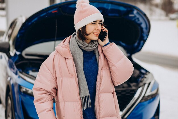 冬季に車が故障した後、若い女性が電話をかけている