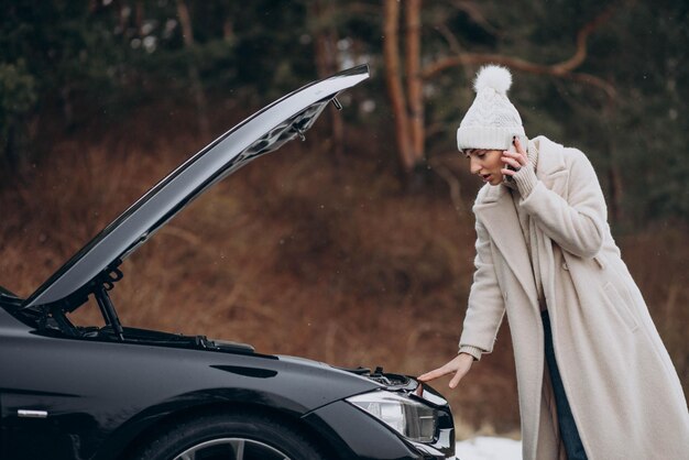 Young woman calling on the phone after her car brokedown in winter season