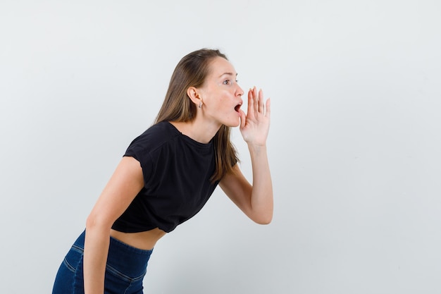 Foto gratuita giovane donna che chiama qualcuno in camicetta nera e sembra impaziente.