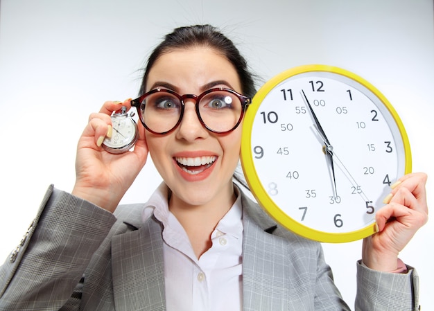 Foto gratuita la giovane donna non vede l'ora di tornare a casa dal brutto ufficio. tenendo l'orologio e aspettando cinque minuti prima della fine. concetto di guai, affari o problemi con la salute mentale di chi lavora in ufficio.