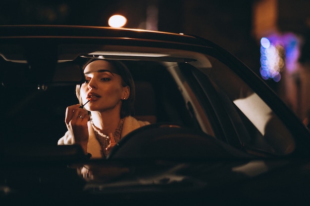 Free photo young woman in car looking into a car mirror