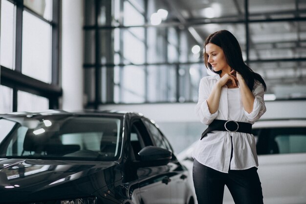 Young woman in a car showroom choosing a car