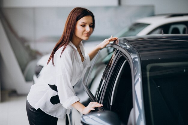 Young woman in a car showroom choosing a car