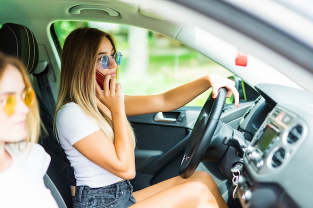 ドライバーが携帯電話を使用して集中力を失っている間、車の中で若い女性。