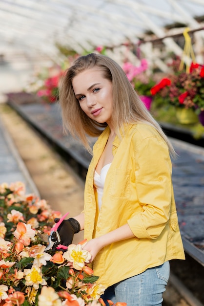 温室の花のお手入れの若い女性