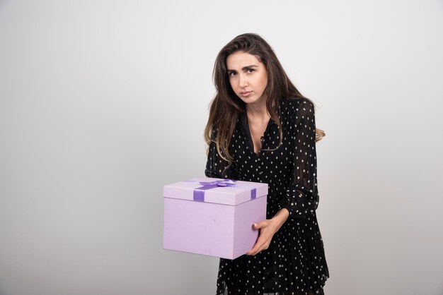Young woman carrying a purple gift box 