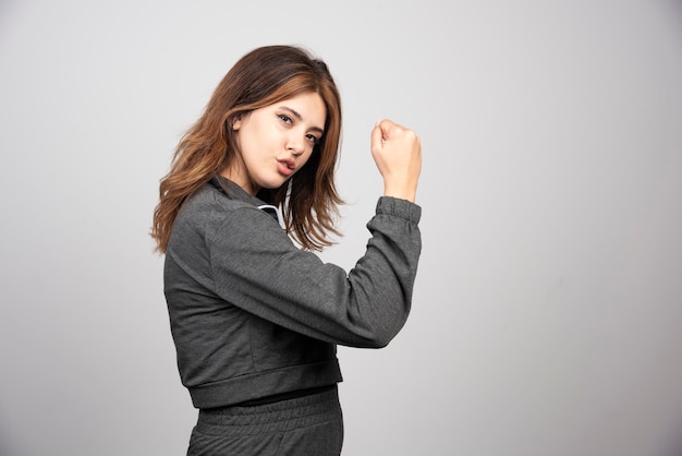 Free photo young woman in casual clothes showing her hand made punch.