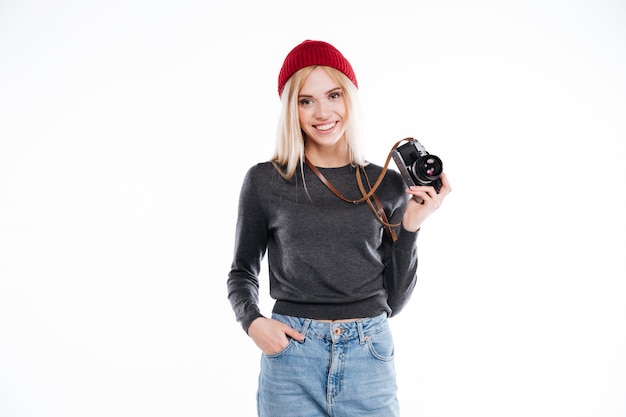 Foto gratuita giovane donna in abbigliamento casual che sta e che tiene retro macchina fotografica