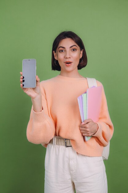 Young woman in casual peach sweater and backpack isolated on green olive color wall