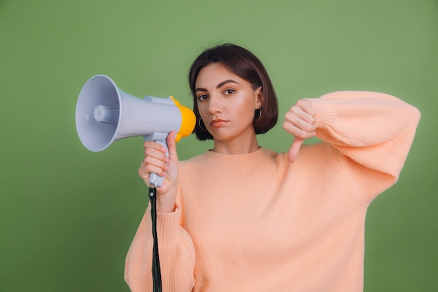 Young woman in casual peach sweater isolated on green olive color wall