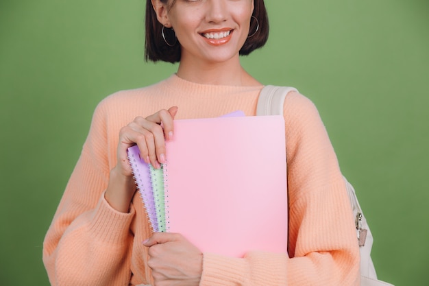 Young woman in casual peach sweater isolated on green olive color wall