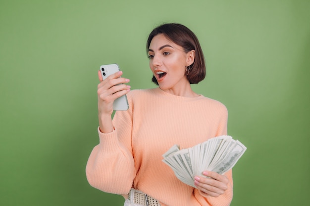 Free photo young woman in casual peach sweater isolated on green olive wall