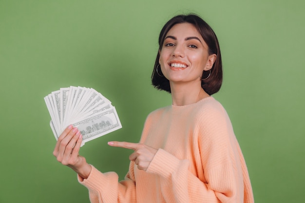 Young woman in casual peach sweater isolated on green olive wall