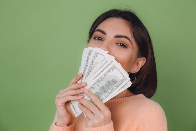 Young woman in casual peach sweater isolated on green olive wall