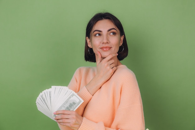 Free photo young woman in casual peach sweater isolated on green olive wall