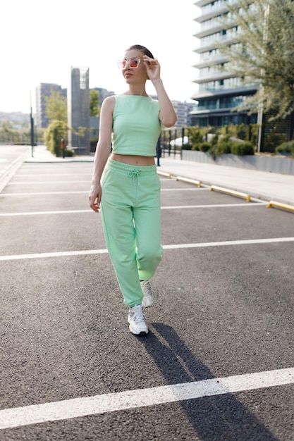 young woman in casual suit using wireless headphones outdoor