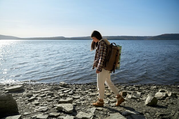 Young woman in casual wear walking along riverside