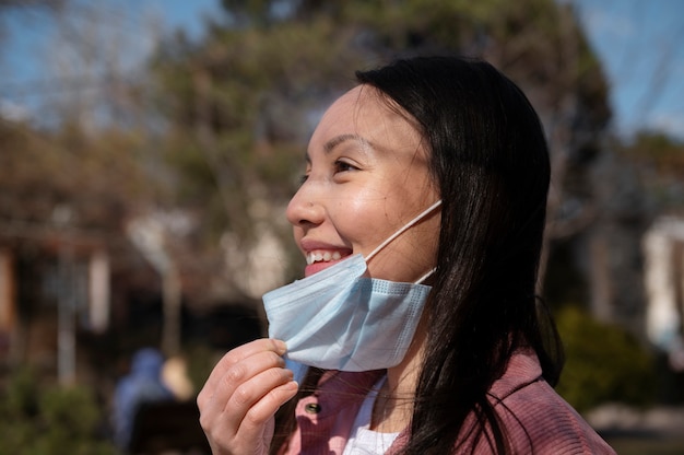 街の屋外でフェイスマスクの制限の解除を祝う若い女性