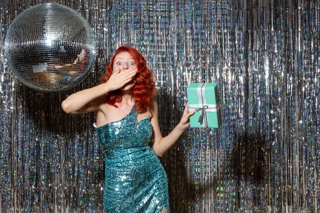 young woman celebrating new year holding present in party on bright curtains