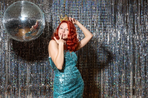 young woman celebrating new year in party holding crown on bright curtains curtains