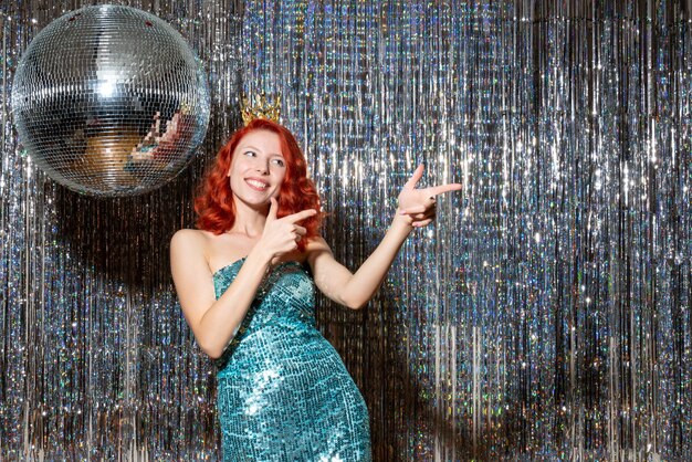 young woman celebrating new year in party with crown on bright curtains curtains