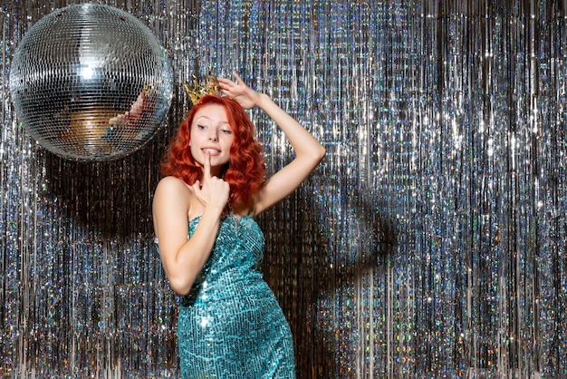 young woman celebrating new year with crown on bright curtains