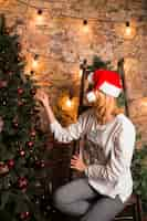 Free photo young woman on chair decorating christmas tree