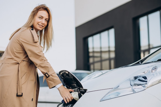 Young woman charging her electric car with charging pistol