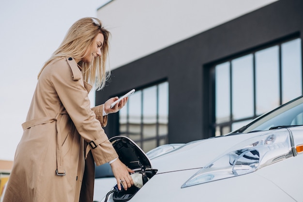 Young woman charging her electric car with charging pistol