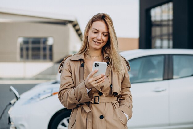 Young woman charging her electric car with charging pistol