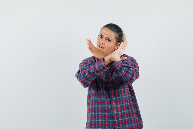 Free photo young woman in checked shirt holding arms crossed and looking angry , front view.