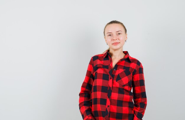 Young woman in checked shirt and looking cheerful. front view.
