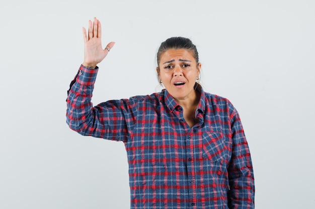 Young woman in checked shirt showing stop sign and looking exhausted , front view.