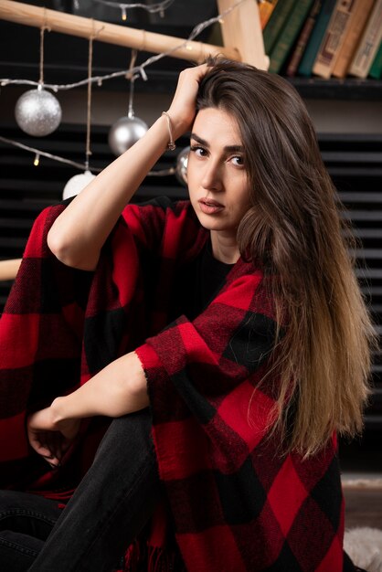 Young woman in checkered plaid posing near Christmas balls.