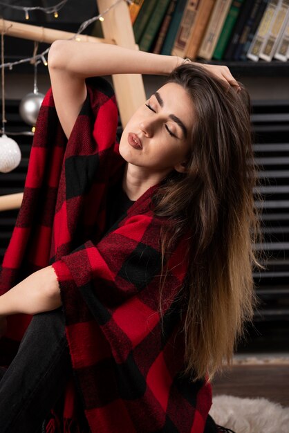 Young woman in checkered plaid posing near Christmas balls.