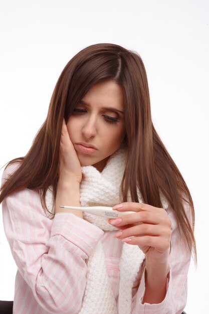 Young woman checking her temperature with a thermometer