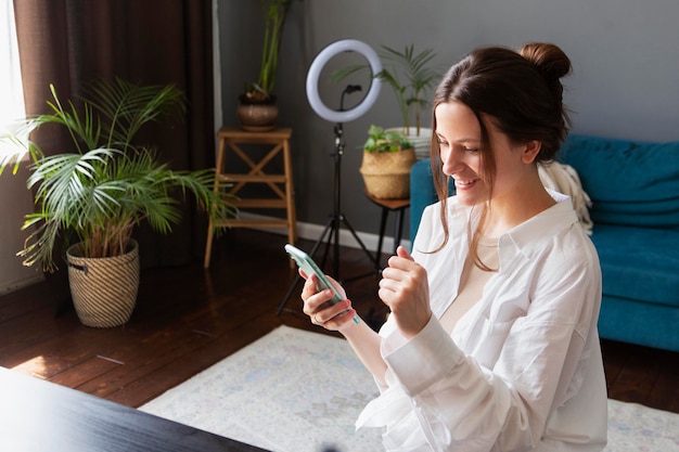 Foto gratuita giovane donna che controlla il suo vlog su uno smartphone