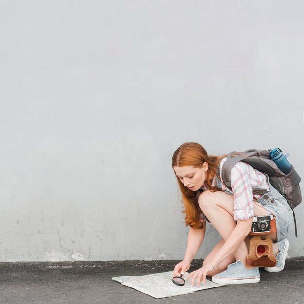 Young woman checking route on map with loupe