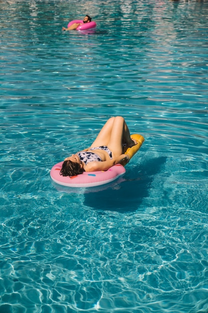 Young woman chilling on inflatable mattress in pool